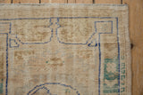 Worn ivory pile of a distressed vintage Oushak rug, with geometric cobalt blue border.