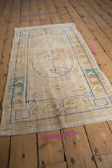 Distressed Oushak rug with aged texture, faded ivory field and faint blue motifs.