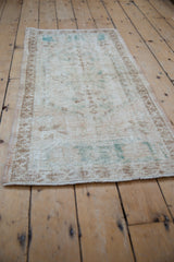 Distressed vintage Oushak runner texture, with faded ivory, brown, and turquoise patterns.