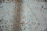 Hand-knotted vintage Oushak rug showing distressed pile, soft ivory, brown, and dusty blue.