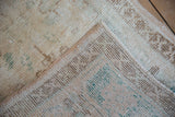 Distressed Oushak rug with textured ivory, brown, turquoise pile and intact selvage.