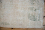 Distressed Oushak runner pile with pale green motifs, visible knot heads, and intact selvage.