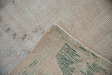 Vintage Distressed Oushak rug's ivory and green textured pile and side selvage.