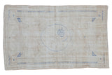 Distressed vintage Oushak rug, ivory and beige tones with a cobalt blue floral roundel.