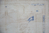 Reverse side of vintage distressed Oushak rug showing blue painted numbers on its foundation.
