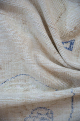 Distressed ivory beige pile of a vintage Oushak rug showing faint cobalt blue patterns.