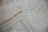 Oushak rug reverse, showing hand-knotted ivory foundation and blue stitching.