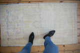 Distressed vintage Oushak rug texture revealing faded blue and gold floral patterns.