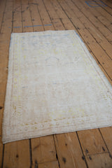 Distressed vintage Oushak runner's texture with worn ivory pile and faint blue floral details.