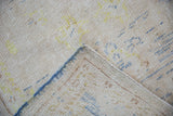 Distressed vintage Oushak rug corner revealing worn texture, exposed foundation, and blue selvage.