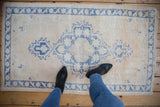 Distressed vintage Oushak rug, ivory field with pale cobalt blue medallion and border.