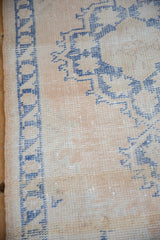 Close-up of the distressed Oushak rug's worn pile, showing pale cobalt blue on ivory.