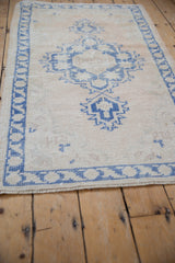 Distressed vintage Turkish Oushak corner with worn texture, ivory, pale blue geometric border, fringe.