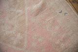 Evenly worn pile on a distressed Oushak rug showing pale pink and beige knot heads.