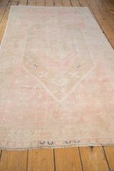 A long perspective view of the distressed Oushak runner's pale pink and beige geometric pattern.