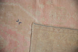 Hand-woven beige foundation of a vintage Turkish rug with a corner revealing the low pink pile.