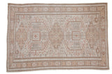 Vintage distressed Oushak carpet, alternating geometric medallions and primitive floral motifs in muted beige and ivory.