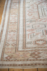 Distressed Oushak border showing geometric patterns and worn pile in muted beige and coral.