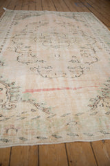 Vintage Distressed Oushak carpet with worn texture, faded ivory scrolling pattern, and prominent red stripe.
