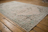 Distressed vintage Oushak corner highlights mostly even wear, ivory, seafoam, and charcoal vinery.