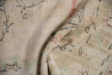 Distressed vintage Oushak rug pile showing textured wear and faint scrolling vinery in soft hues.