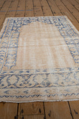 Vintage distressed Oushak rug detail: worn ivory pile revealing foundation, faded blue border.
