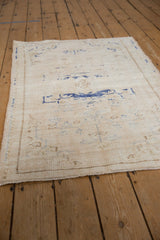 Textured pile and faded cobalt blue motifs on a distressed vintage Oushak rug corner.