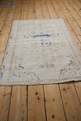 Corner of distressed Oushak rug, showing fringe, intact side selvage, worn pile, and foundation.