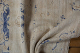 Distressed Oushak rug's ivory pile, cobalt blue details, and intact side cording.