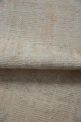 Textured pile of a distressed Oushak rug in ivory, beige, and subtle seafoam.