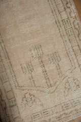 Close view of distressed vintage Oushak rug's ivory and pale brown pile with visible foundation.