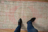 Distressed Oushak runner showcasing soft, worn pile and faded rose floral motifs, underfoot.