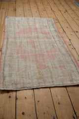 Distressed vintage Oushak rug texture revealing rose, ivory, and grey with wear to knot heads.
