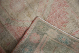 Soft pile of distressed vintage Oushak rug with visible foundation and side cord.