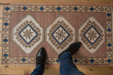 Distressed vintage Oushak rug showcasing a mauve abrashed field with ivory and denim blue motifs.