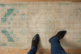 Distressed vintage Oushak runner in faded ivory and green, showing low pile and foundation.