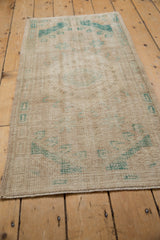 Distressed vintage Oushak rug pile with mostly even wear, faded ivory and green.