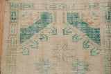 Distressed vintage Oushak rug, showing even wear on ivory and forest green pile.