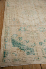 Distressed vintage Oushak rug showing worn pile, visible foundation, ivory, and faded green.