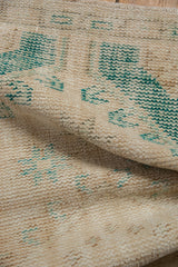 Distressed vintage Oushak rug texture, showing worn ivory and muted green pile with foundation.
