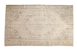 Distressed Oushak carpet with faded floral medallion, blush cream, ivory, and ocean green hues.