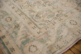 Textured pile of distressed Oushak rug, with visible knot heads, muted green, and blush tones.