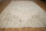 Distressed vintage Oushak rug border showing faded green vinery on blush cream.