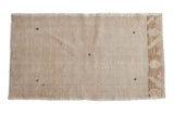 Vintage distressed Oushak rug featuring an open beige field with subtle blue diamond shapes and abrash.