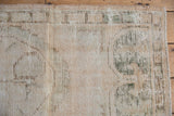 Detail of distressed Oushak rug showing worn knot heads, faded green, and beige tones.