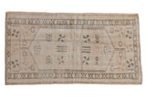 Distressed vintage Oushak rug with ivory, beige, and oxidized silver medallion.