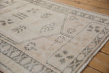 Distressed Oushak rug's low pile and visible knot heads, with ivory, beige, and oxidized silver patterns.