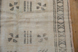 Distressed ivory and beige patterned border with subtle field motifs.