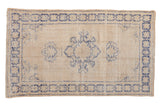 Distressed vintage Oushak rug, faded cobalt blue medallion, floral border on ivory beige.