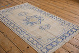 Distressed Oushak rug showing worn ivory field and faded cobalt blue starburst border.